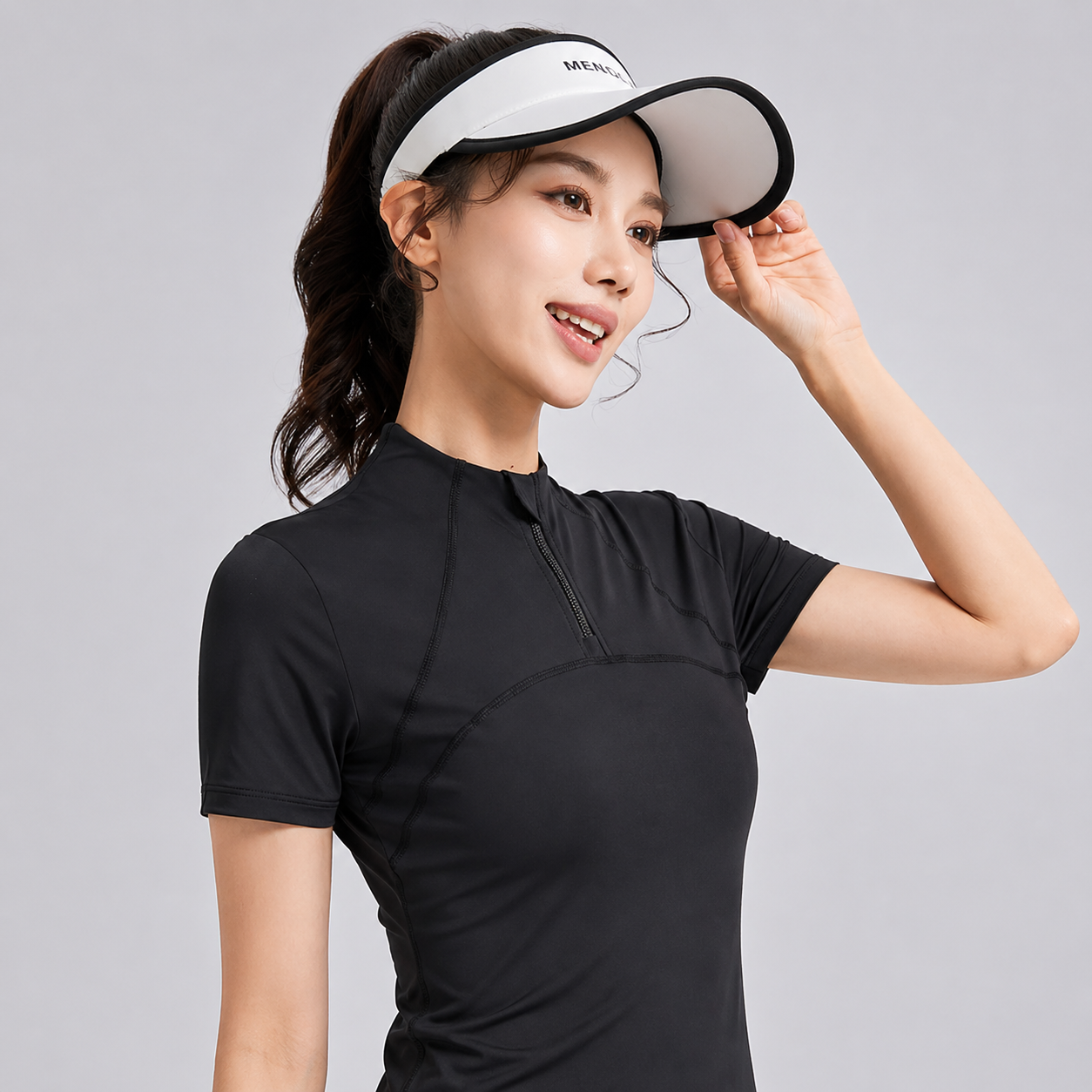 Woman wearing a black athletic shirt and a visor on a gray background