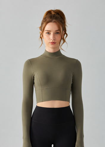 Woman wearing a green long-sleeve crop top and black leggings on a gray background
