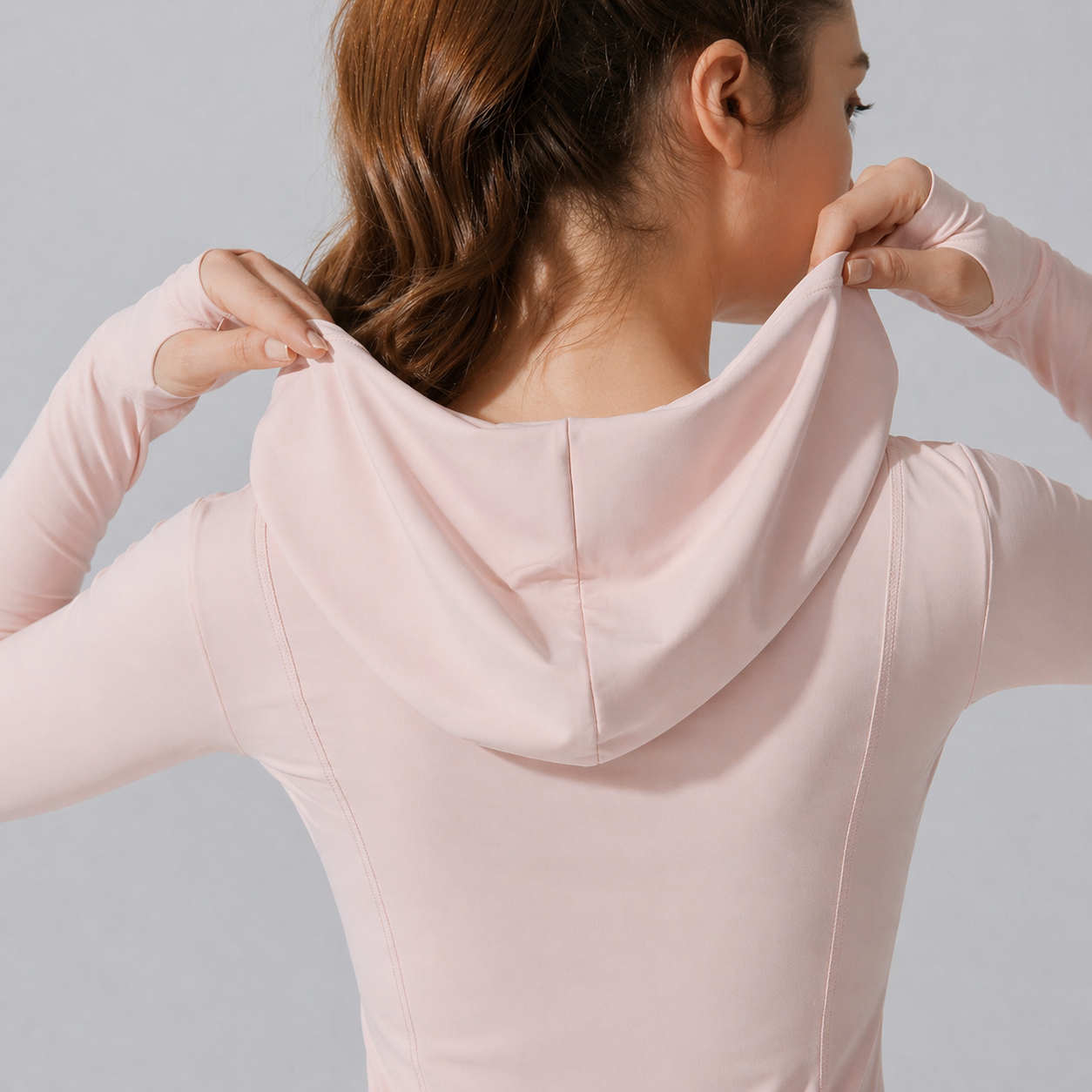 Person wearing a light pink hoodie against a neutral background