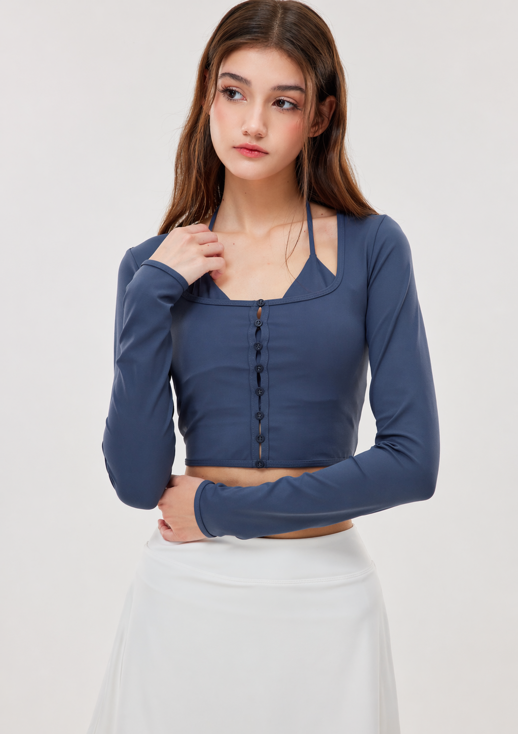 Woman wearing a blue long-sleeve crop top against a white background