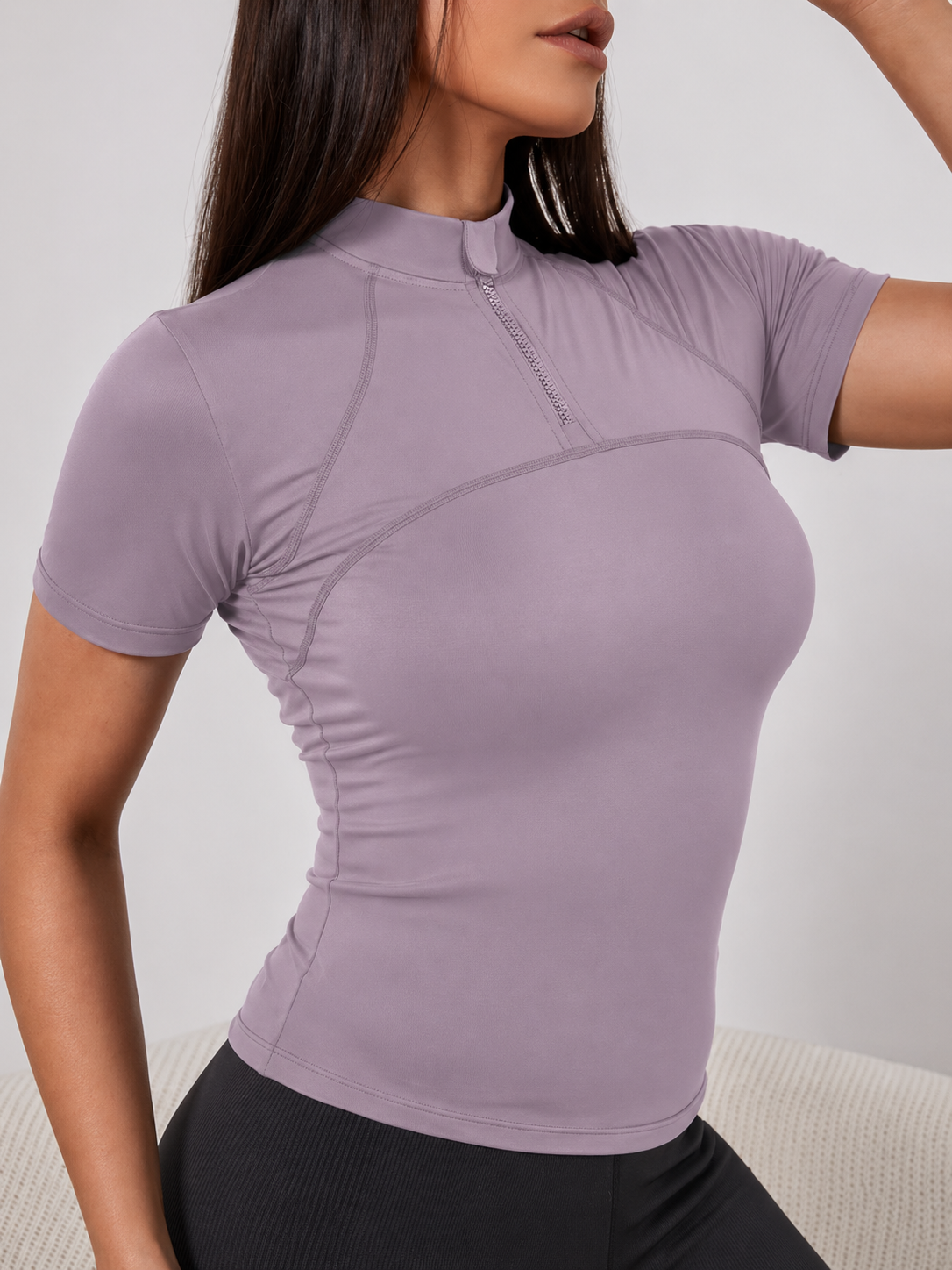 Woman wearing a fitted purple athletic top against a neutral background