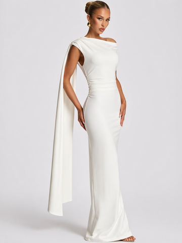Woman wearing a white evening gown with a cape on a plain background