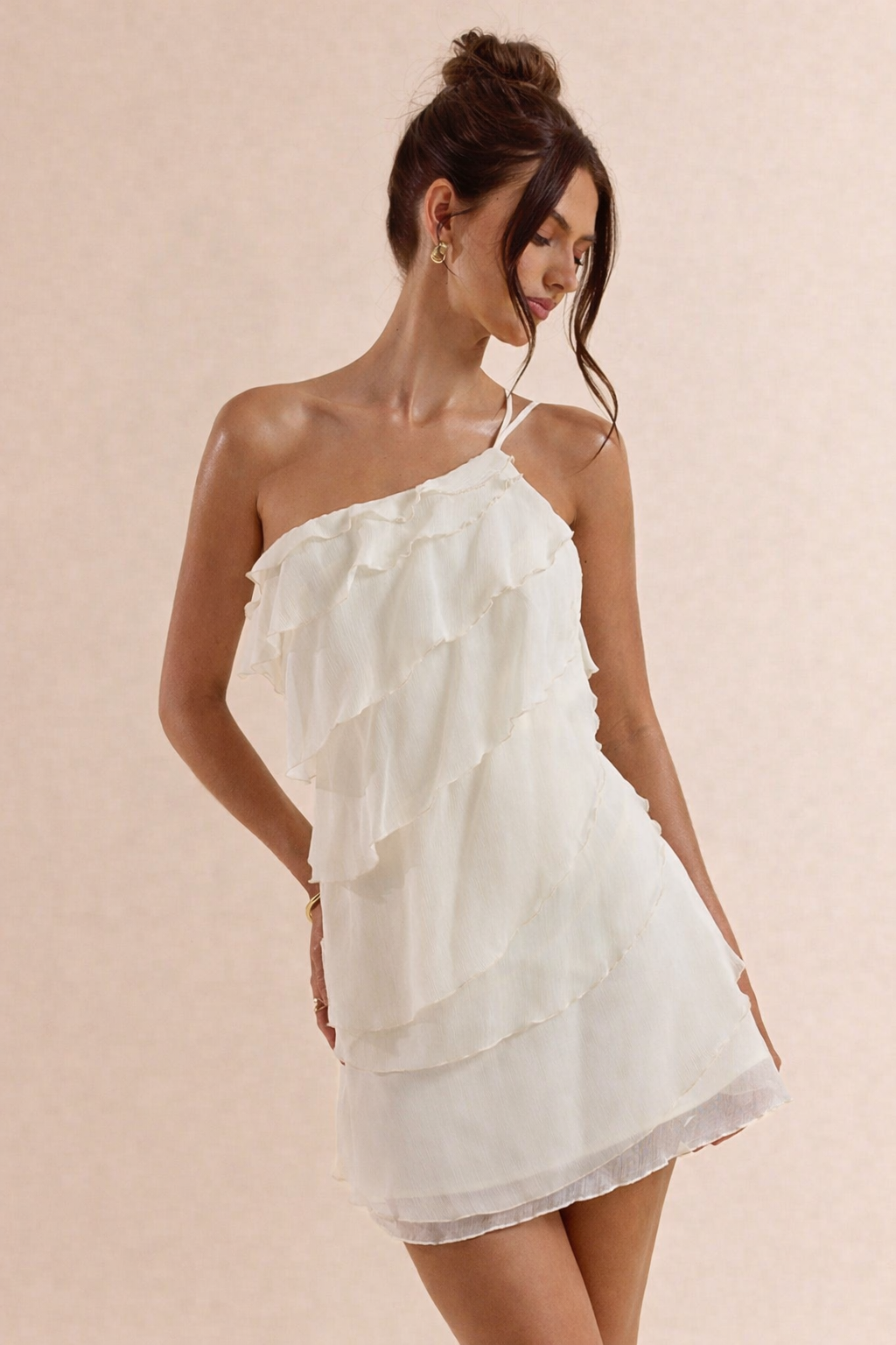 Woman wearing a white one-shoulder dress against a beige background