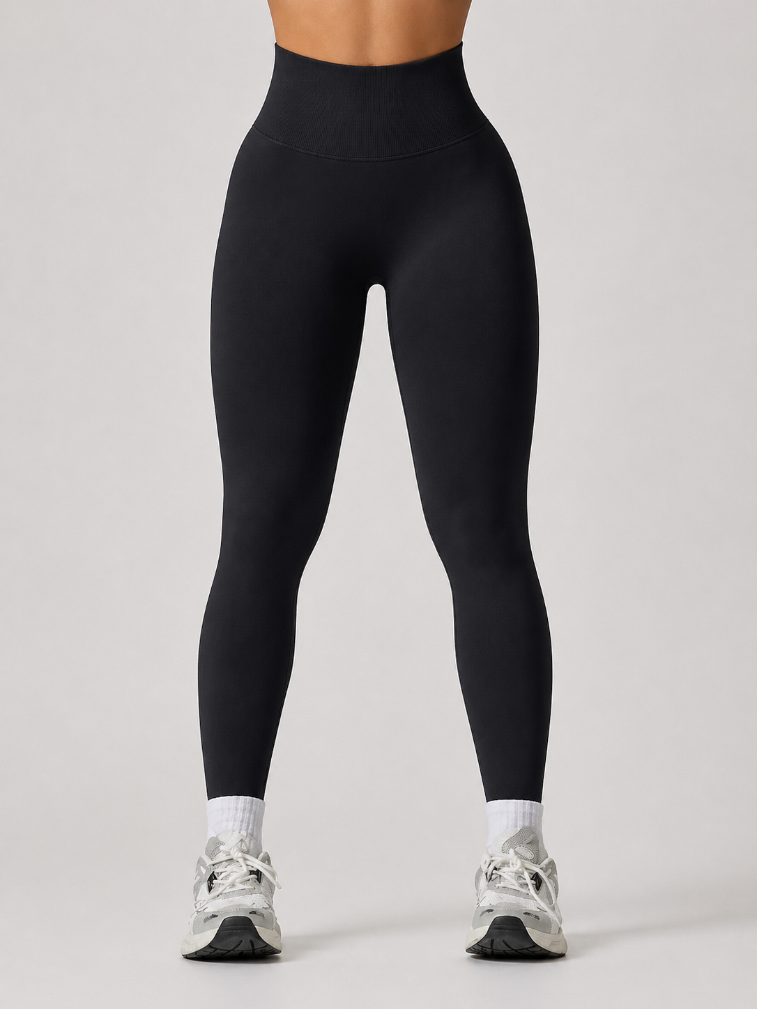 Person wearing black leggings on a plain background