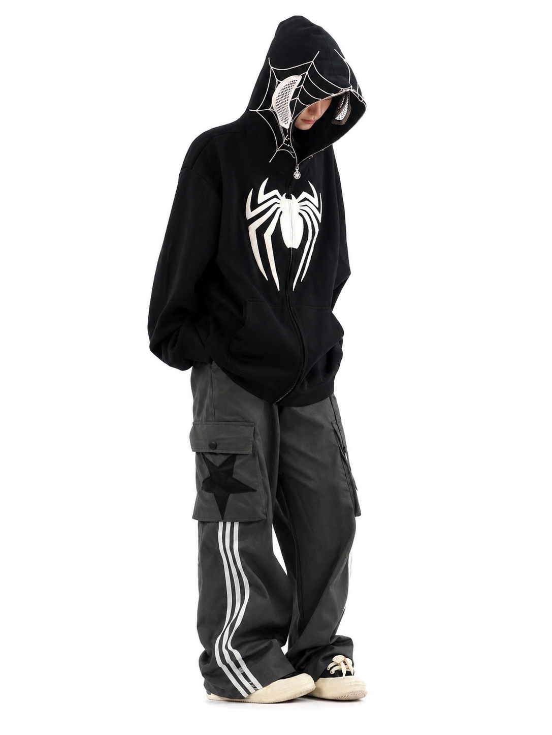 Person wearing a black hoodie with a spider logo and cargo pants on a white background