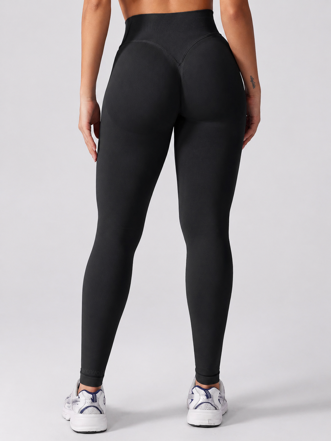Person wearing black leggings on a plain background