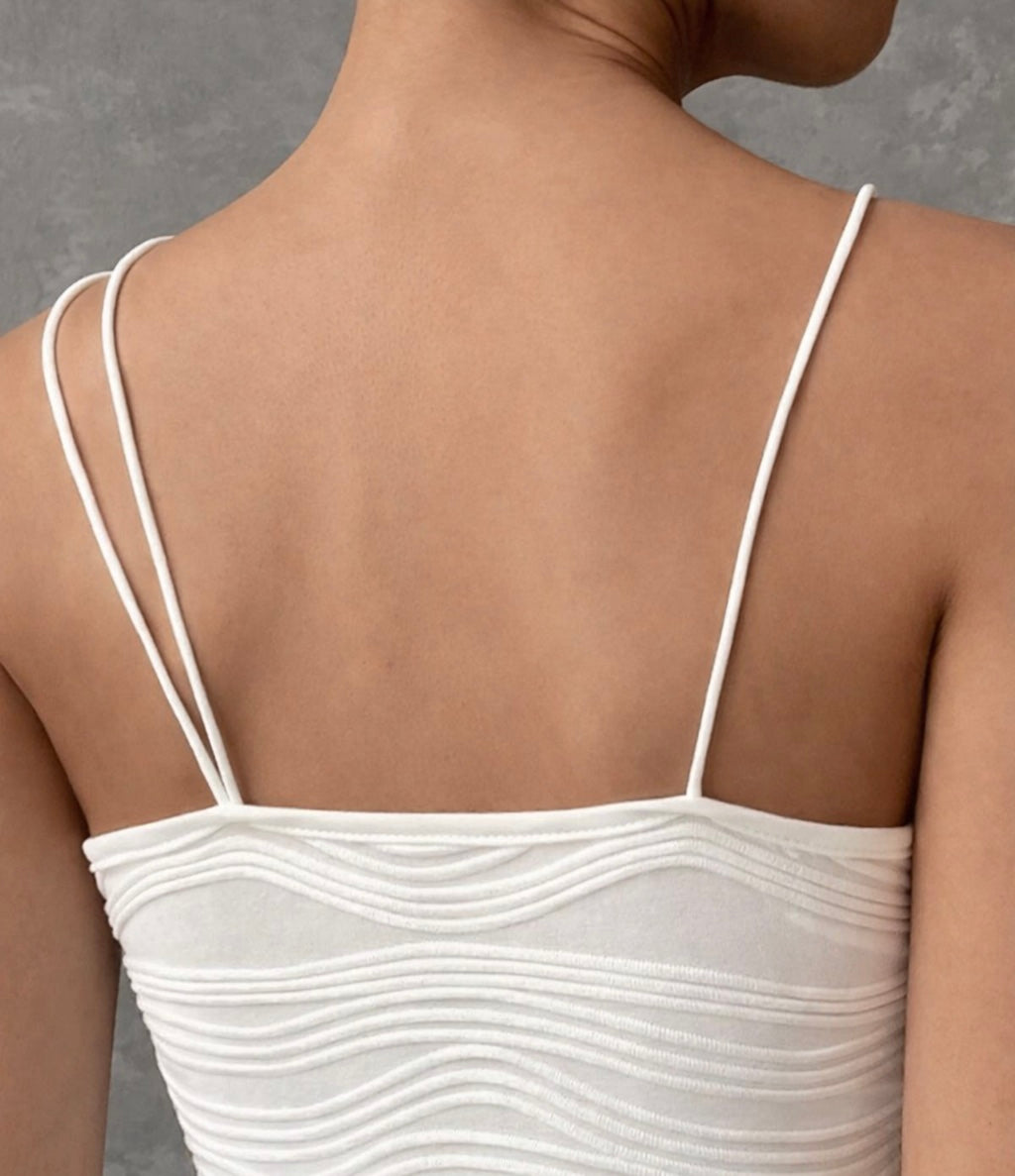 White spaghetti strap top worn by a person against a gray background