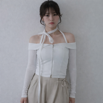 Woman wearing a white off-shoulder top with a tie detail against a plain background
