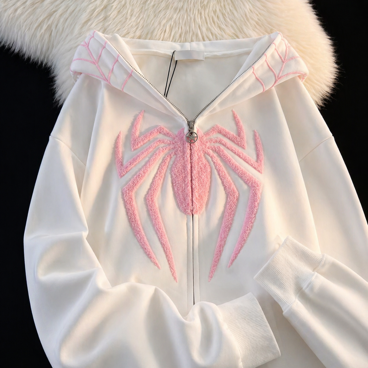 White hoodie with pink spider design on a black background
