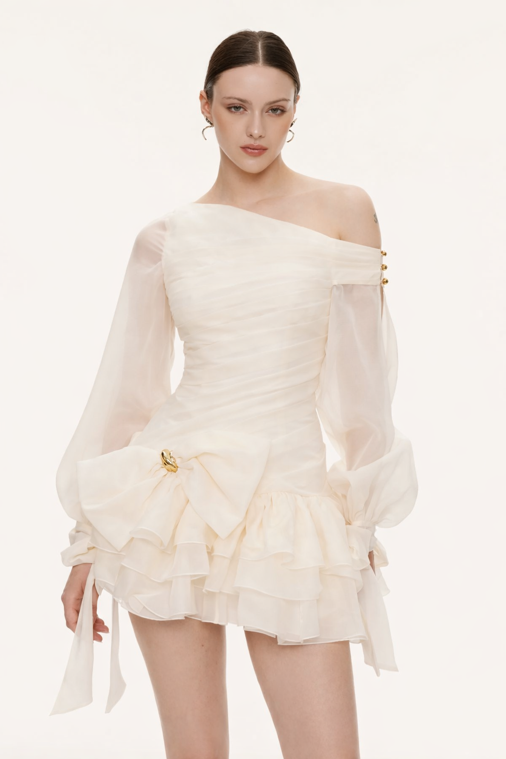 Woman wearing a white off-shoulder dress with long sleeves on a white background