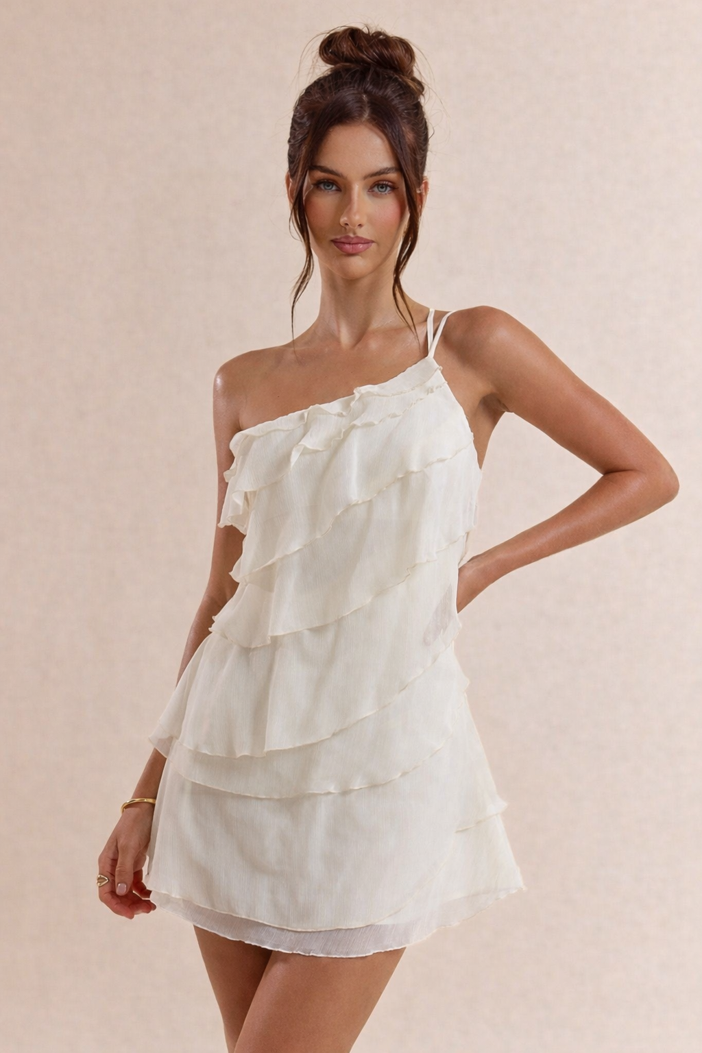 Woman wearing a white one-shoulder dress against a beige background