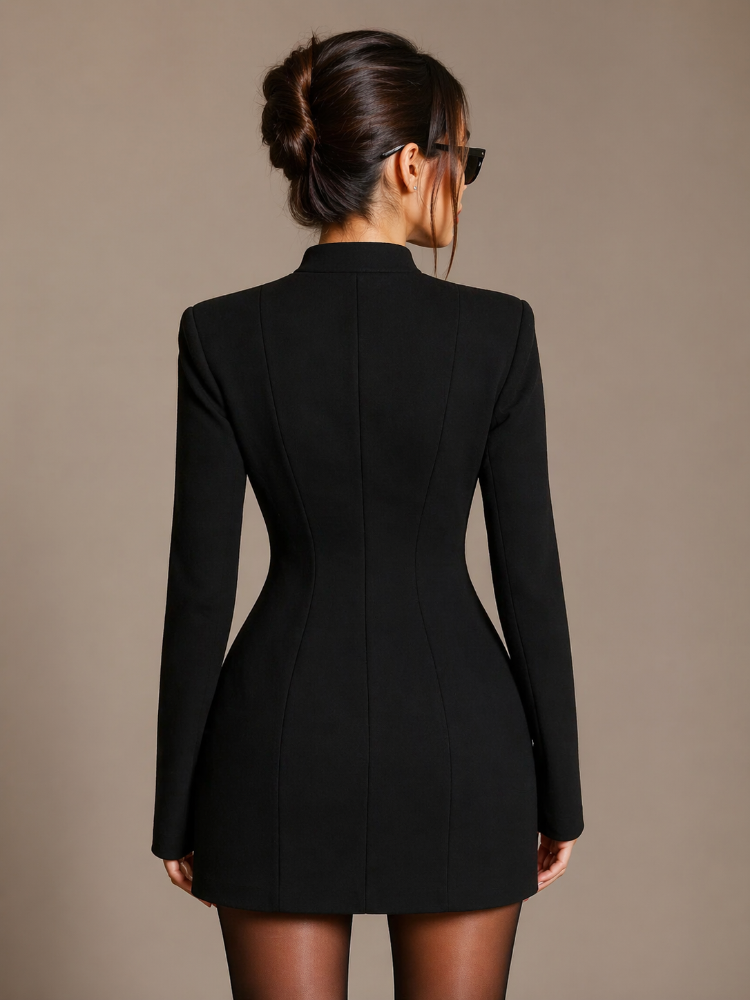 Woman wearing a black blazer dress against a beige background