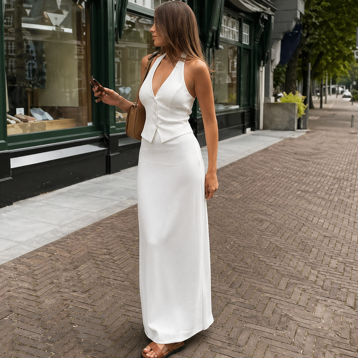 Woman in a white dress walking on a sidewalk with storefronts in the background