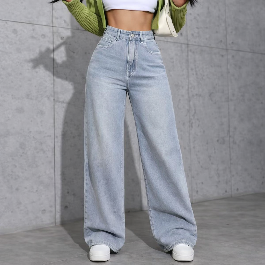 Person wearing light blue wide-leg jeans against a gray concrete wall.