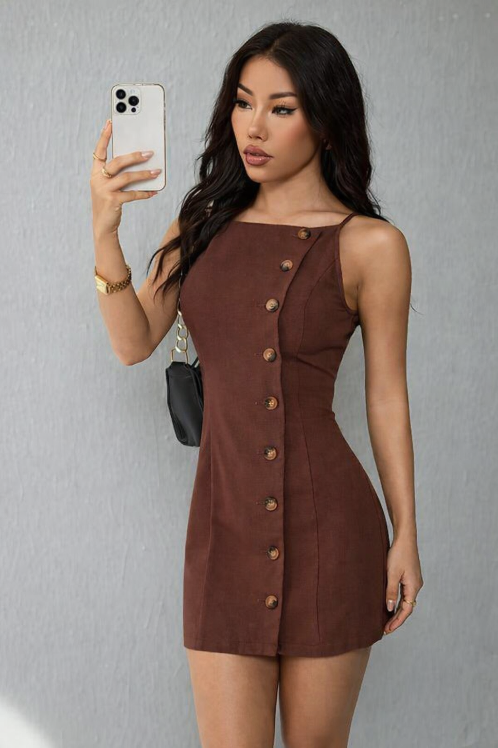 Woman taking a selfie wearing a brown button-up dress against a gray background