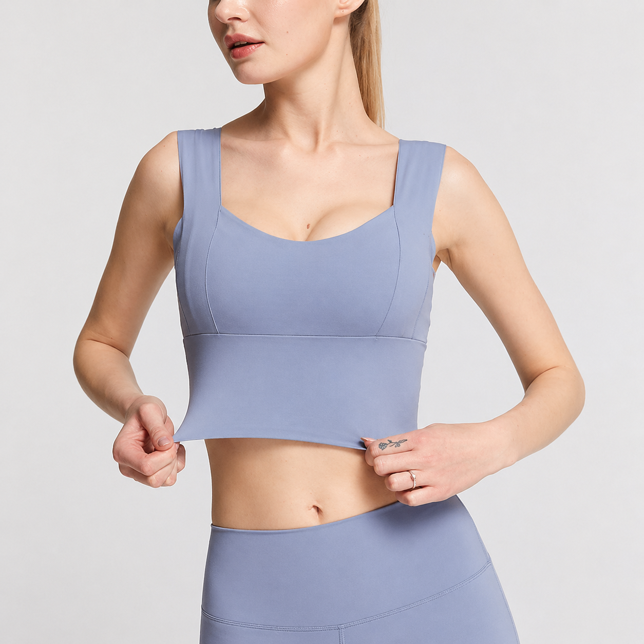 Woman wearing a light purple sports bra and leggings on a plain background