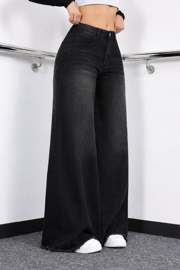 Person wearing black wide-leg jeans in a minimal indoor setting
