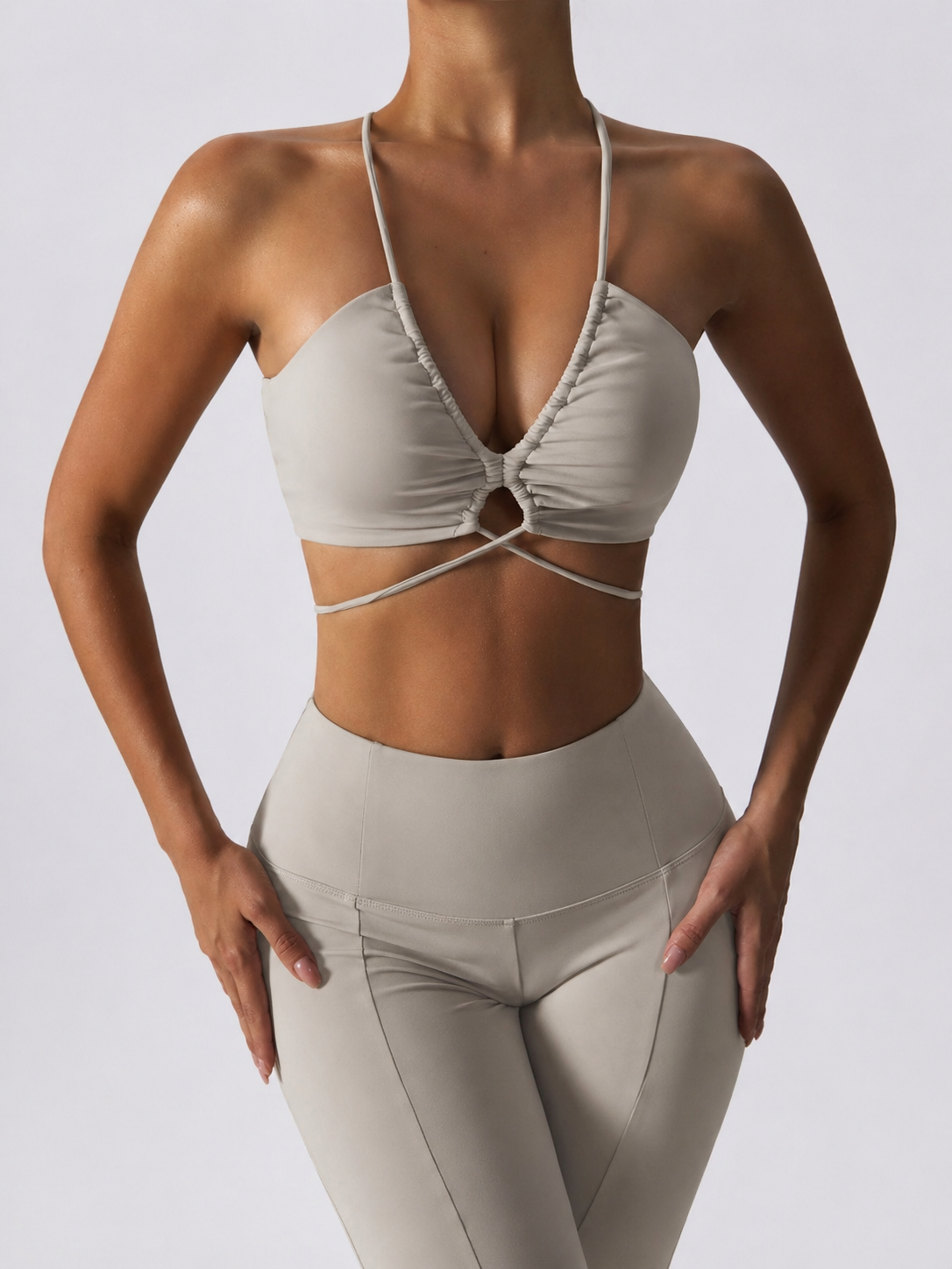 Person wearing a beige sports bra and leggings on a plain background