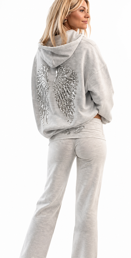 Woman wearing a gray hoodie with decorative elements and matching pants on a white background