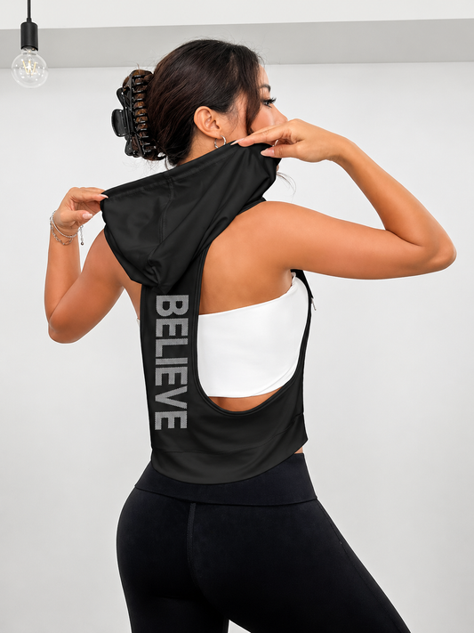 Woman wearing a black tank top with 'BELIEVE' printed on the back against a plain background