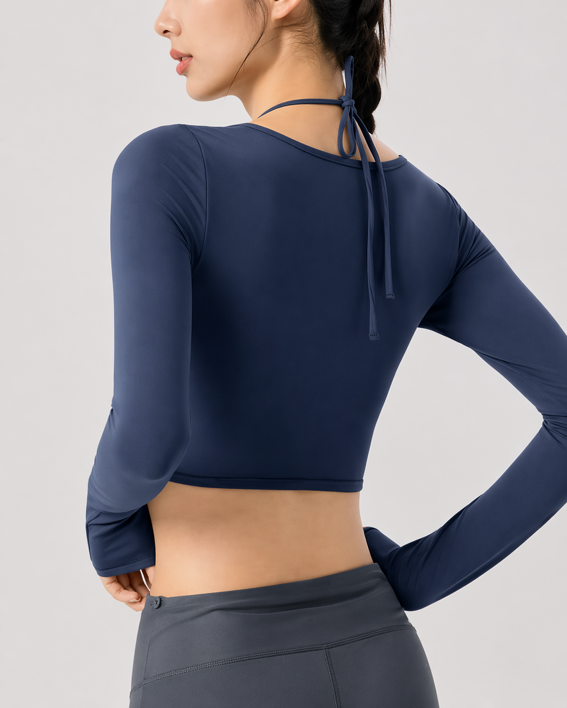 Navy long-sleeve crop top worn by a person on a light gray background