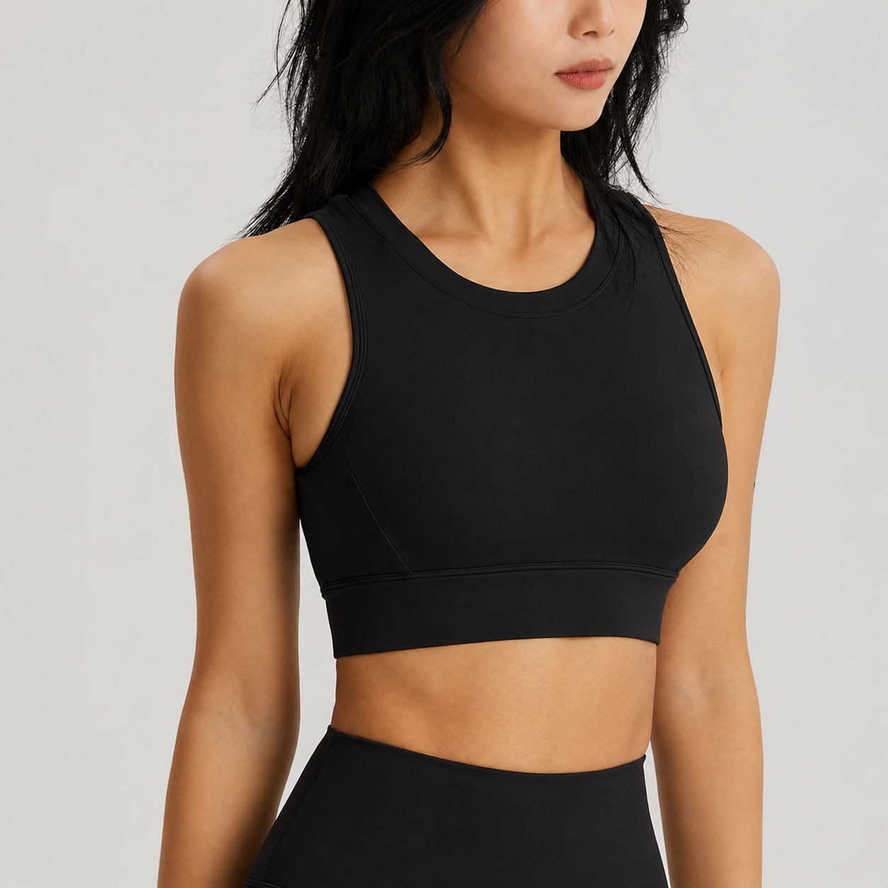 Black sports bra worn by a person on a light gray background