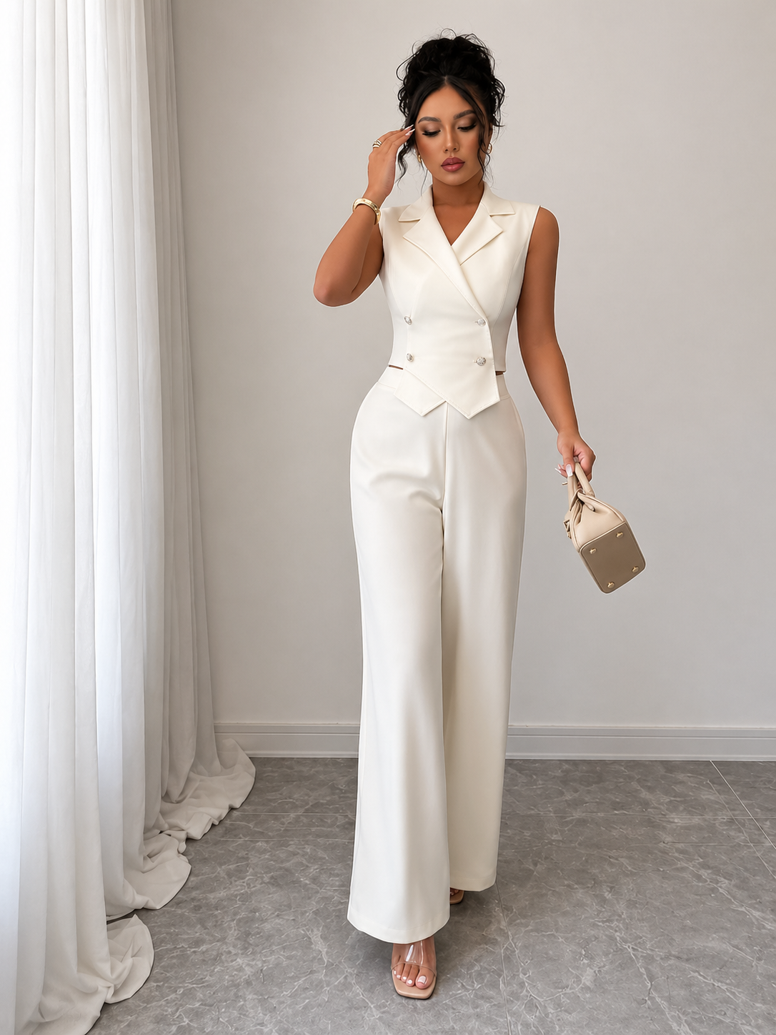 Woman in a white outfit holding a beige handbag in a room with white curtains.