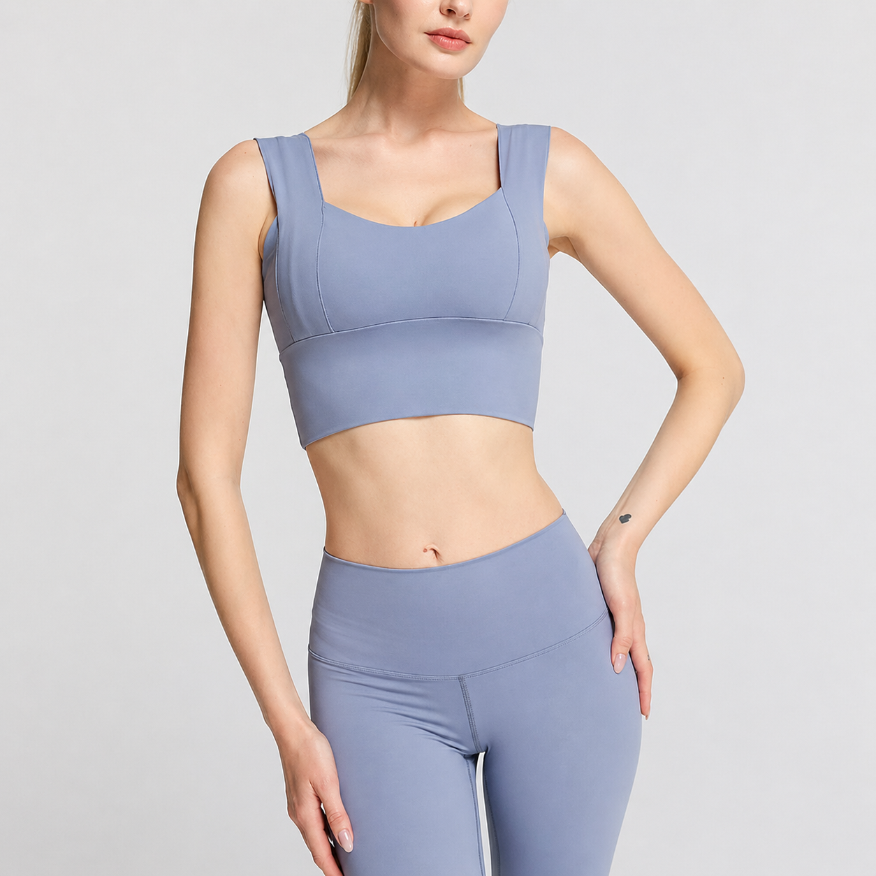 Person wearing a light purple sports bra and leggings set on a gray background