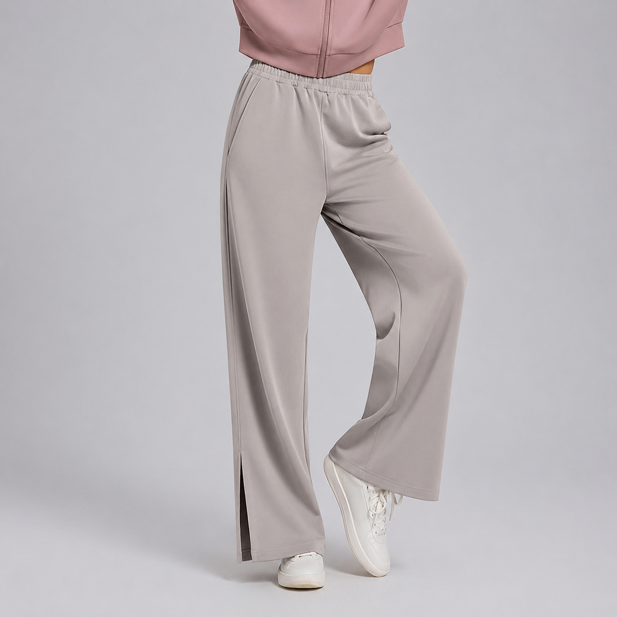 Person wearing light gray wide-leg pants and a pink jacket on a plain background