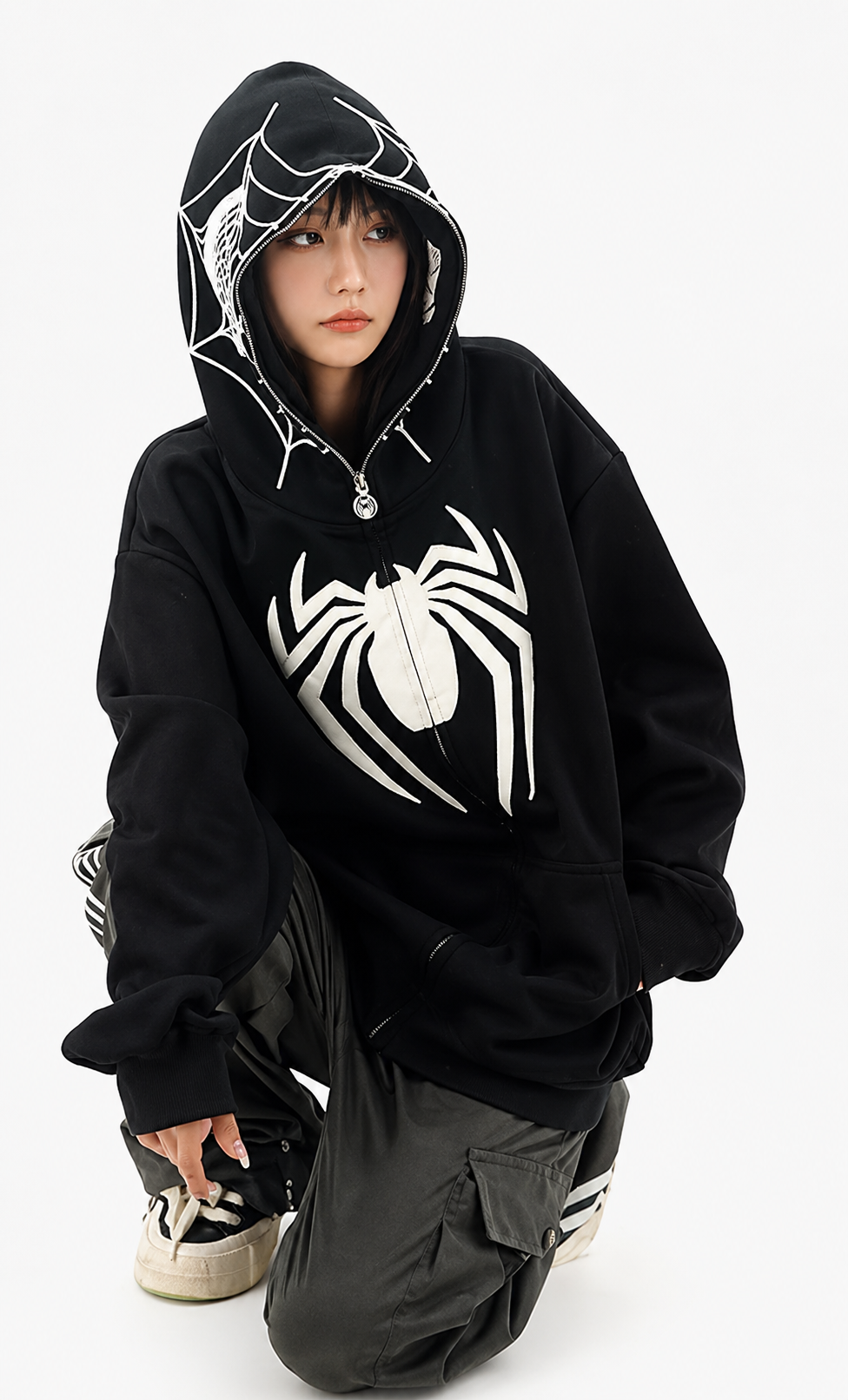 Person wearing a black hoodie with a white spider design on a white background