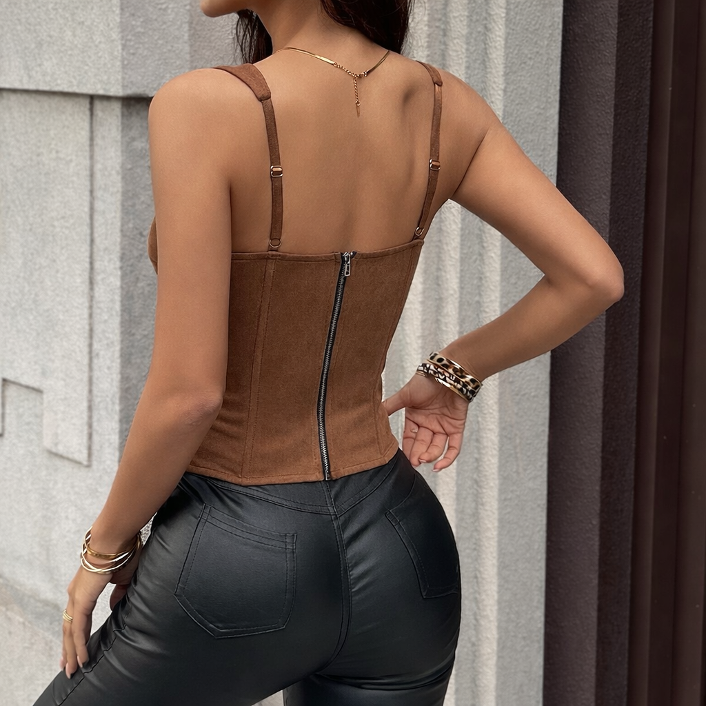 Person wearing a brown leather top and black leather pants against a neutral background