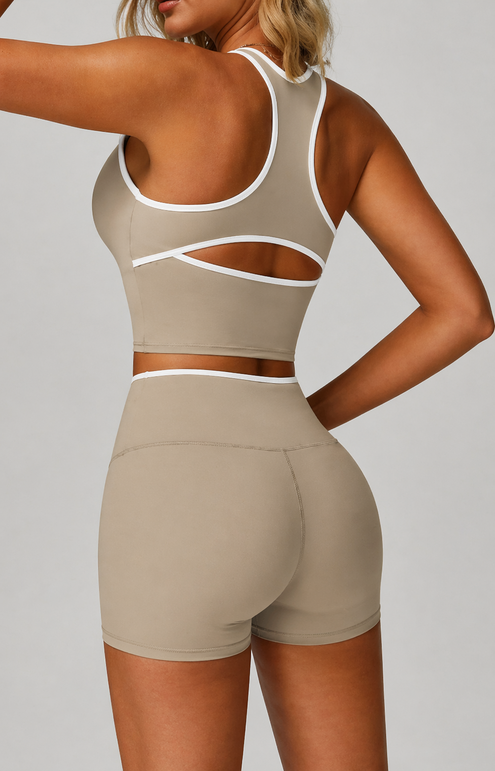 Person wearing a beige sports bra and shorts set on a plain background