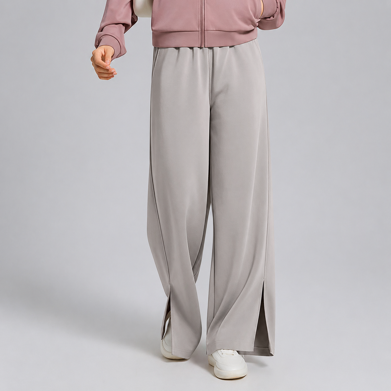 Person wearing light gray wide-leg pants and a pink jacket on a plain background