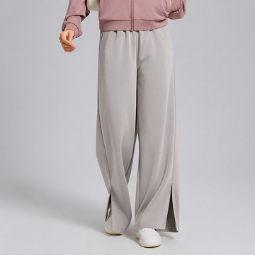 Person wearing light gray wide-leg pants and a pink jacket on a plain background