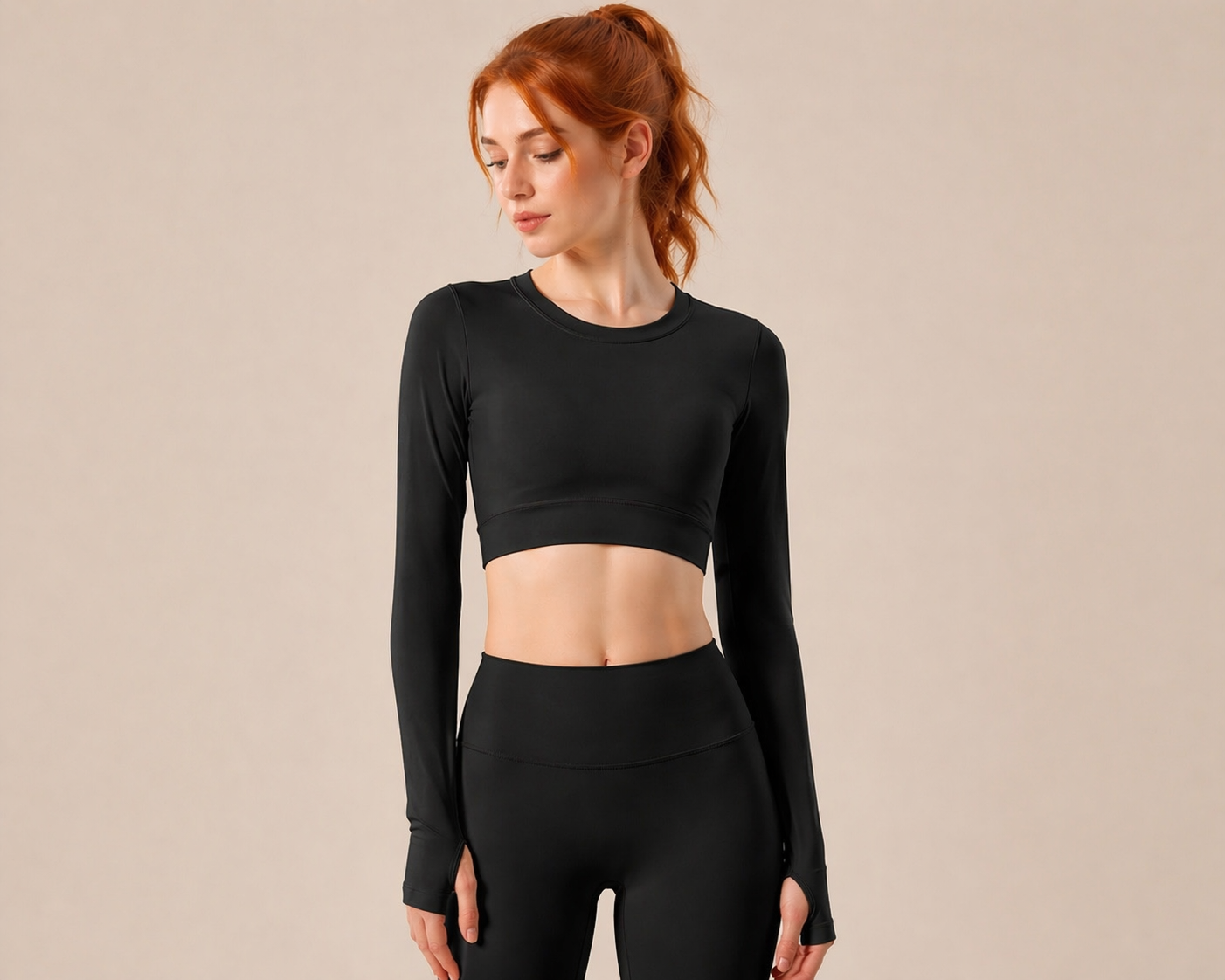 Woman wearing a black long-sleeve crop top and leggings on a beige background