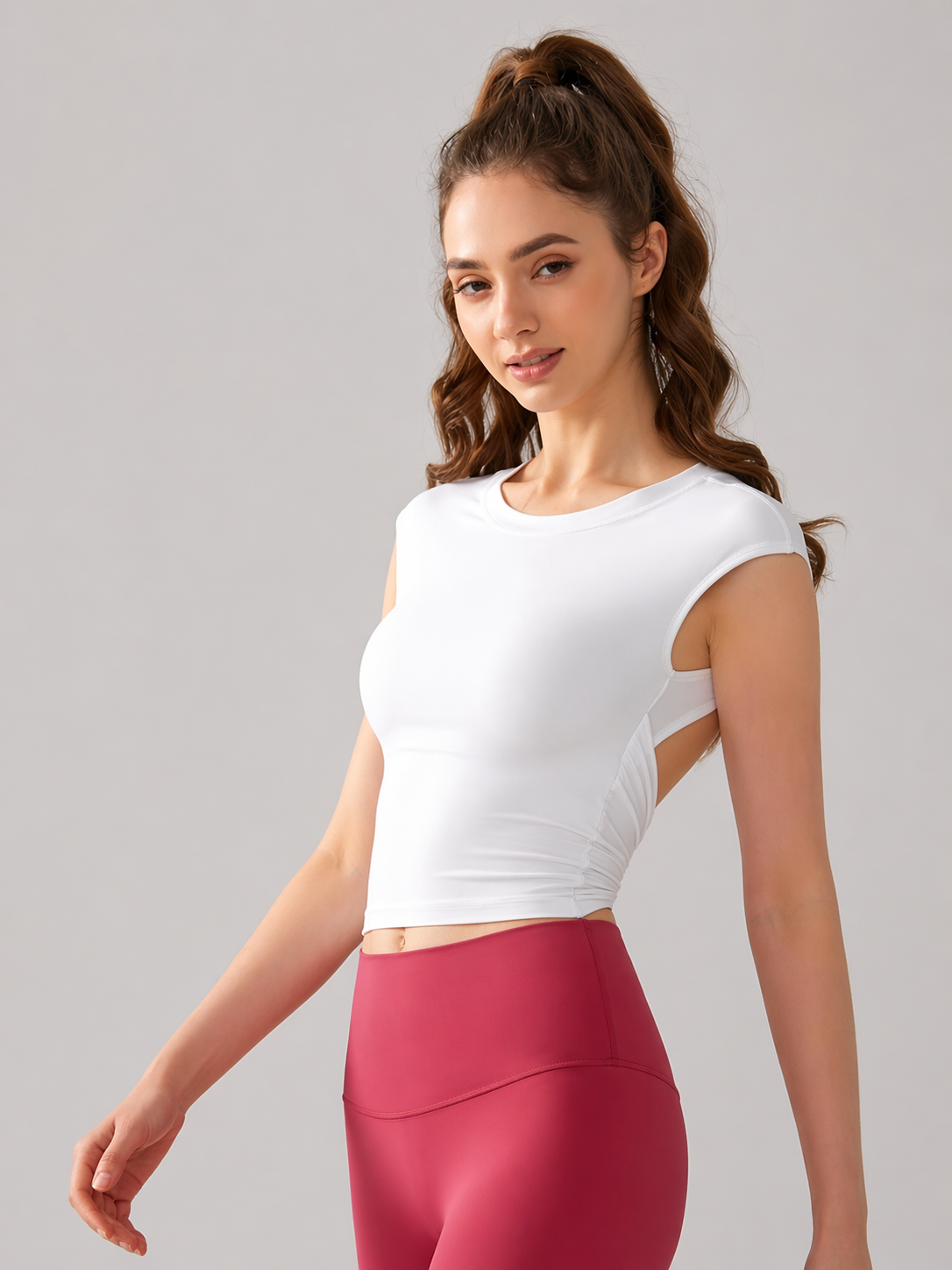 Woman wearing a white crop top and pink leggings on a gray background