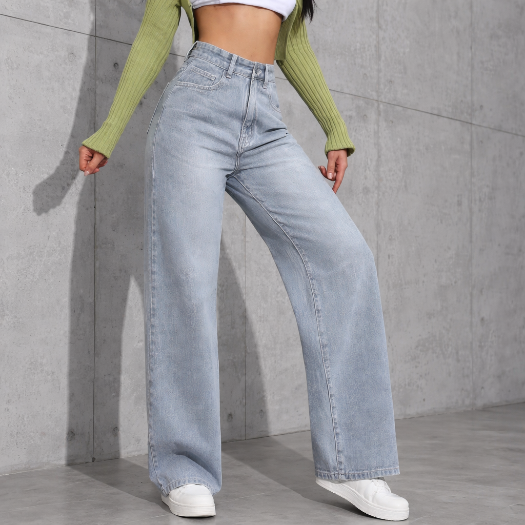 Person wearing light blue jeans and a green sweater against a gray concrete wall.