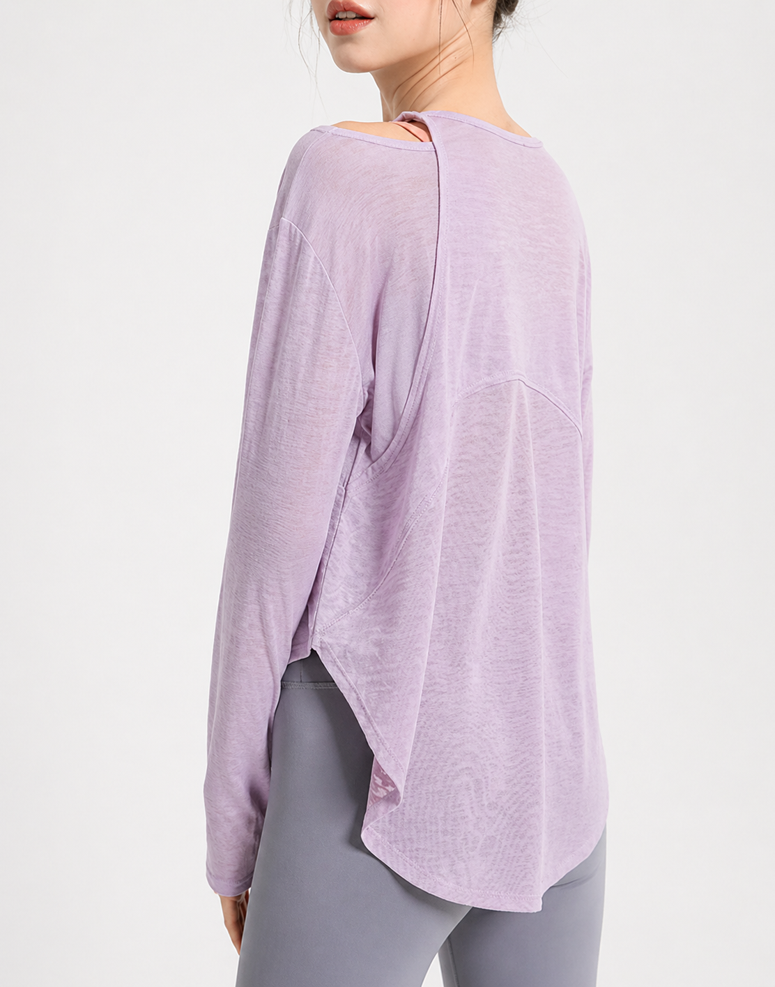 Person wearing a light purple top and gray leggings on a white background