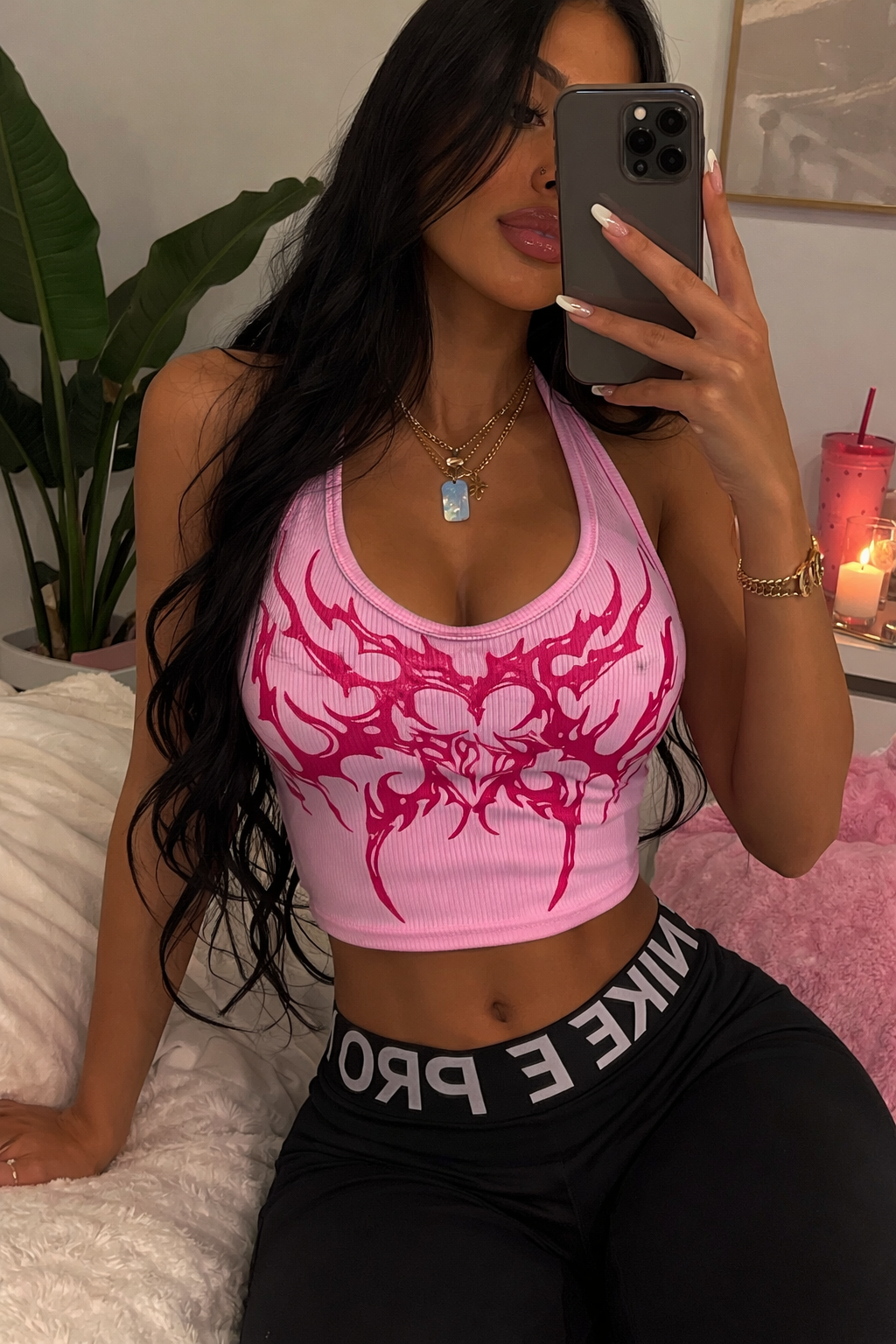 Woman taking a mirror selfie wearing a pink sports bra with a dragon design and black leggings.