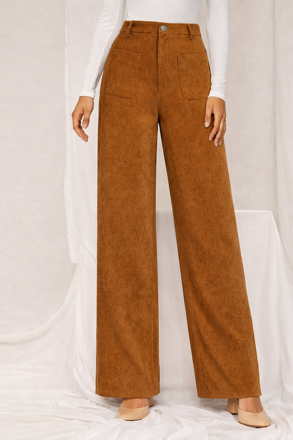 Brown corduroy pants worn by a person on a white background
