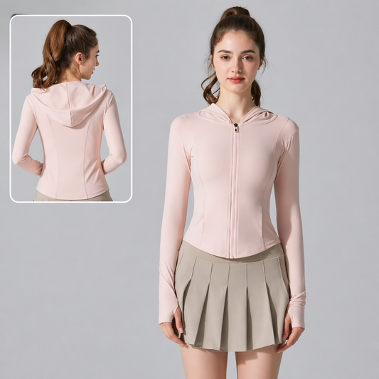 Woman wearing a light pink zip-up hoodie and beige pleated skirt on a gray background