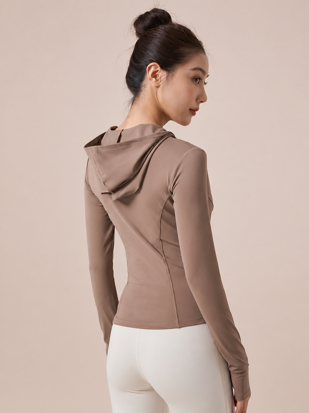 Woman wearing a brown hooded jacket on a beige background