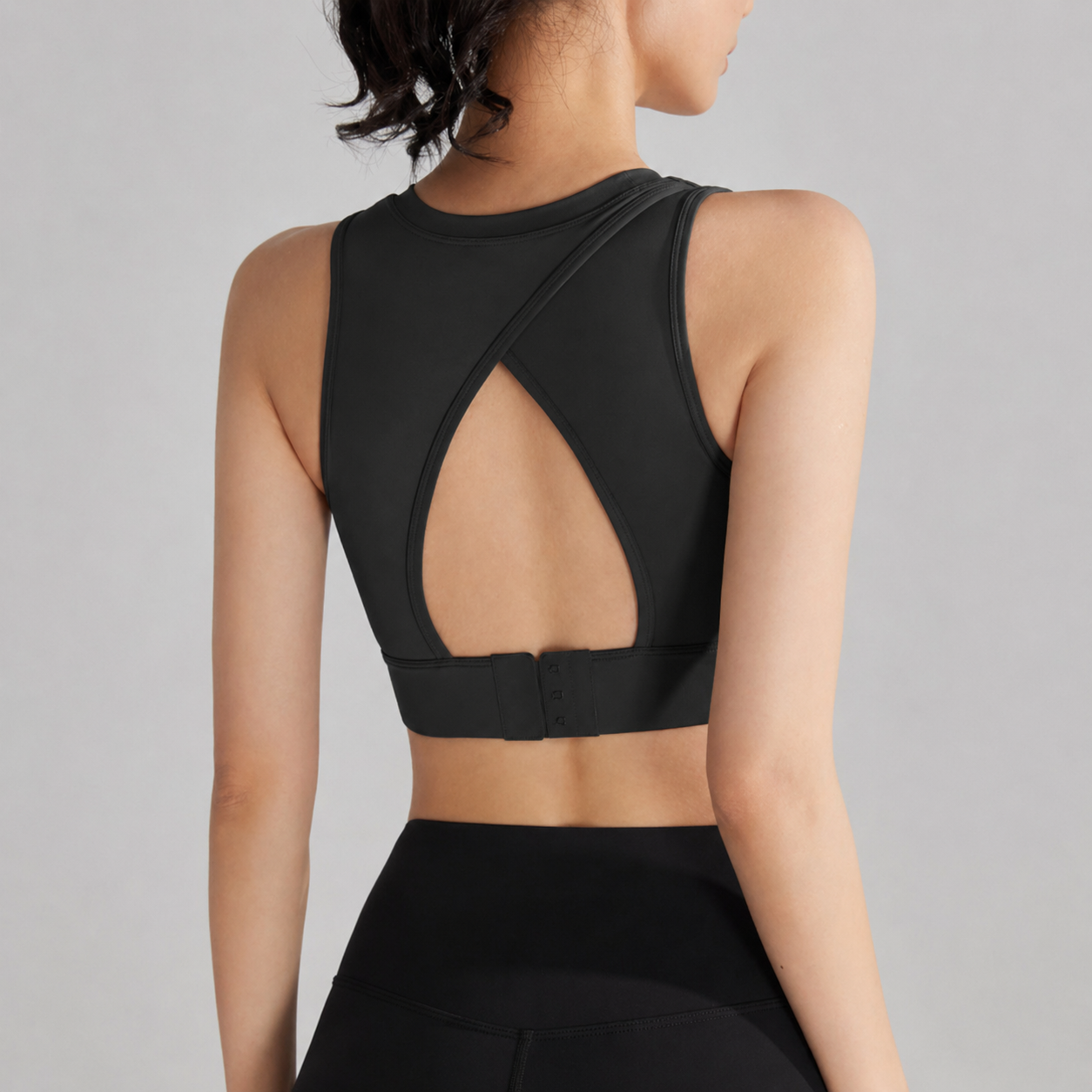 Black sports bra with open back design on a gray background