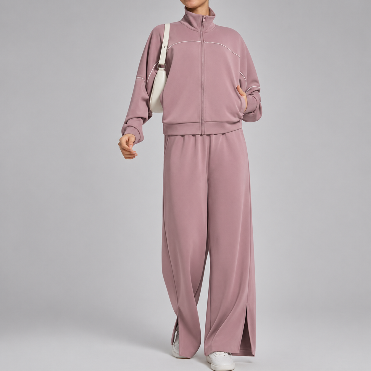 Person wearing a mauve tracksuit on a gray background