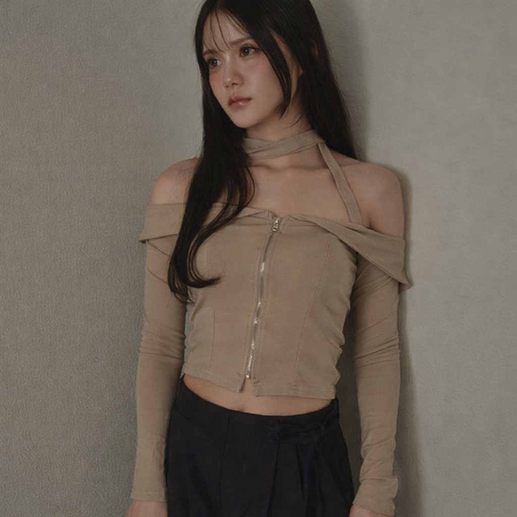 Woman wearing a beige off-shoulder top against a plain background