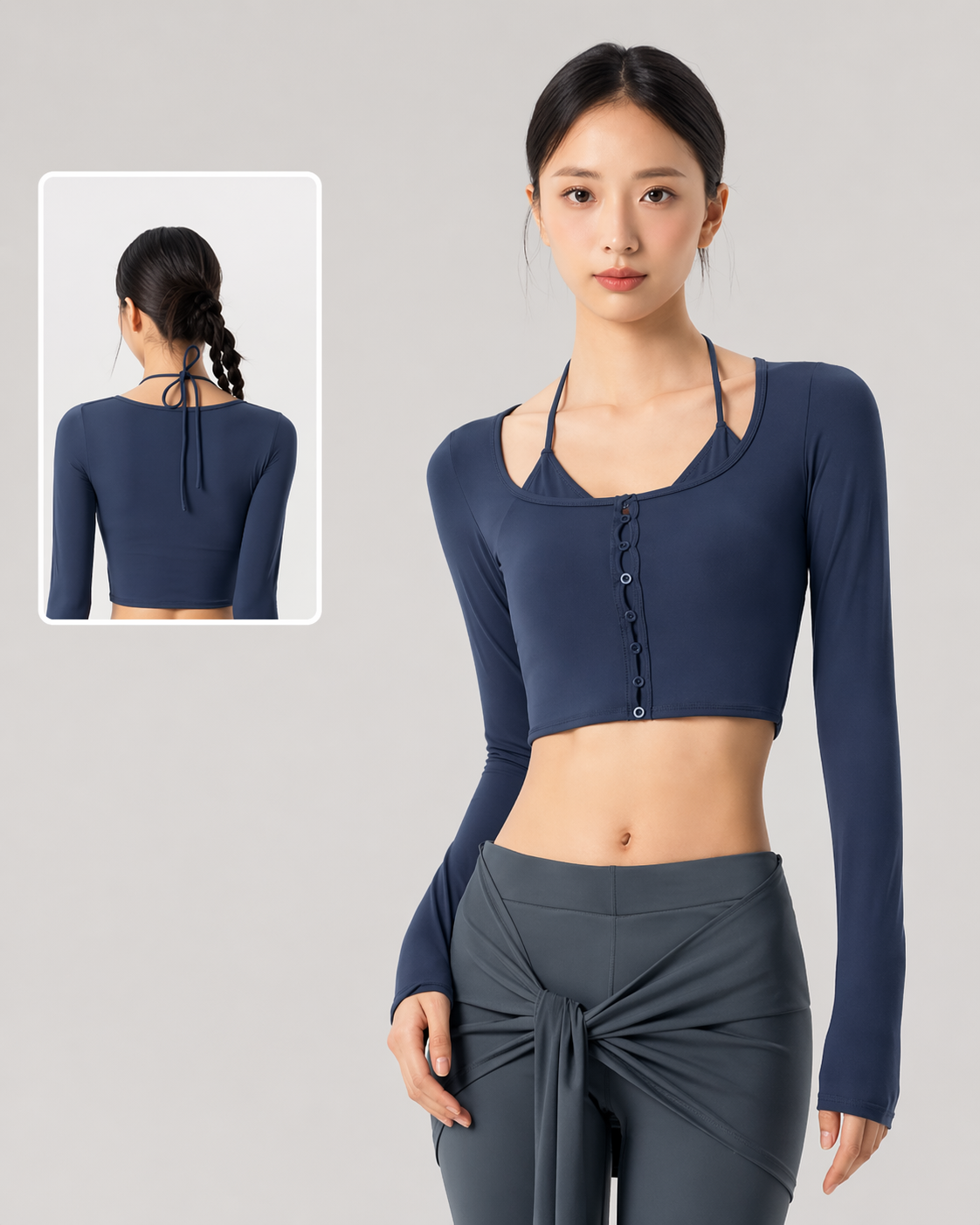 Woman wearing a navy long-sleeve crop top and gray pants on a gray background