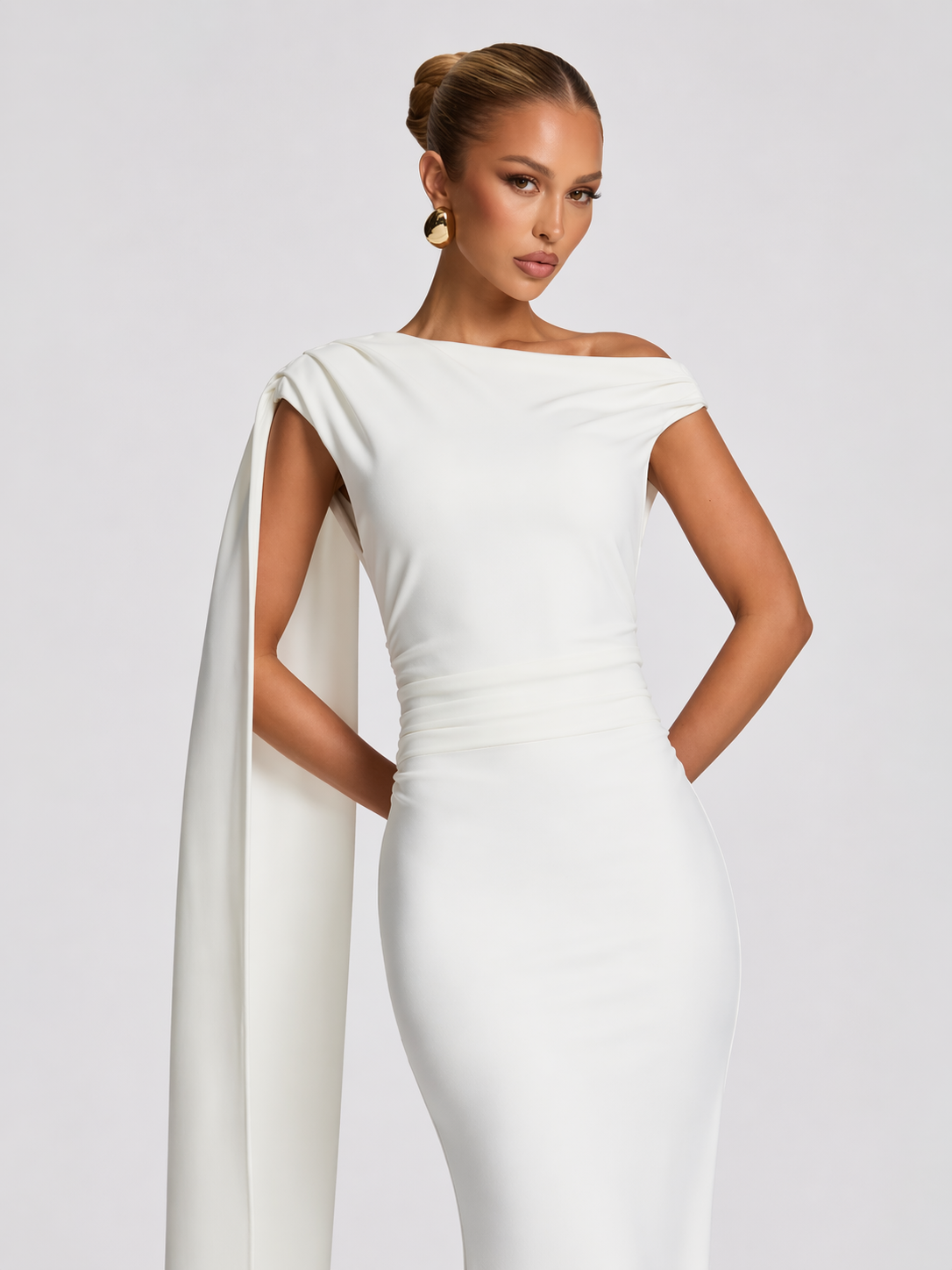 Woman wearing a white gown with a cape on a plain background