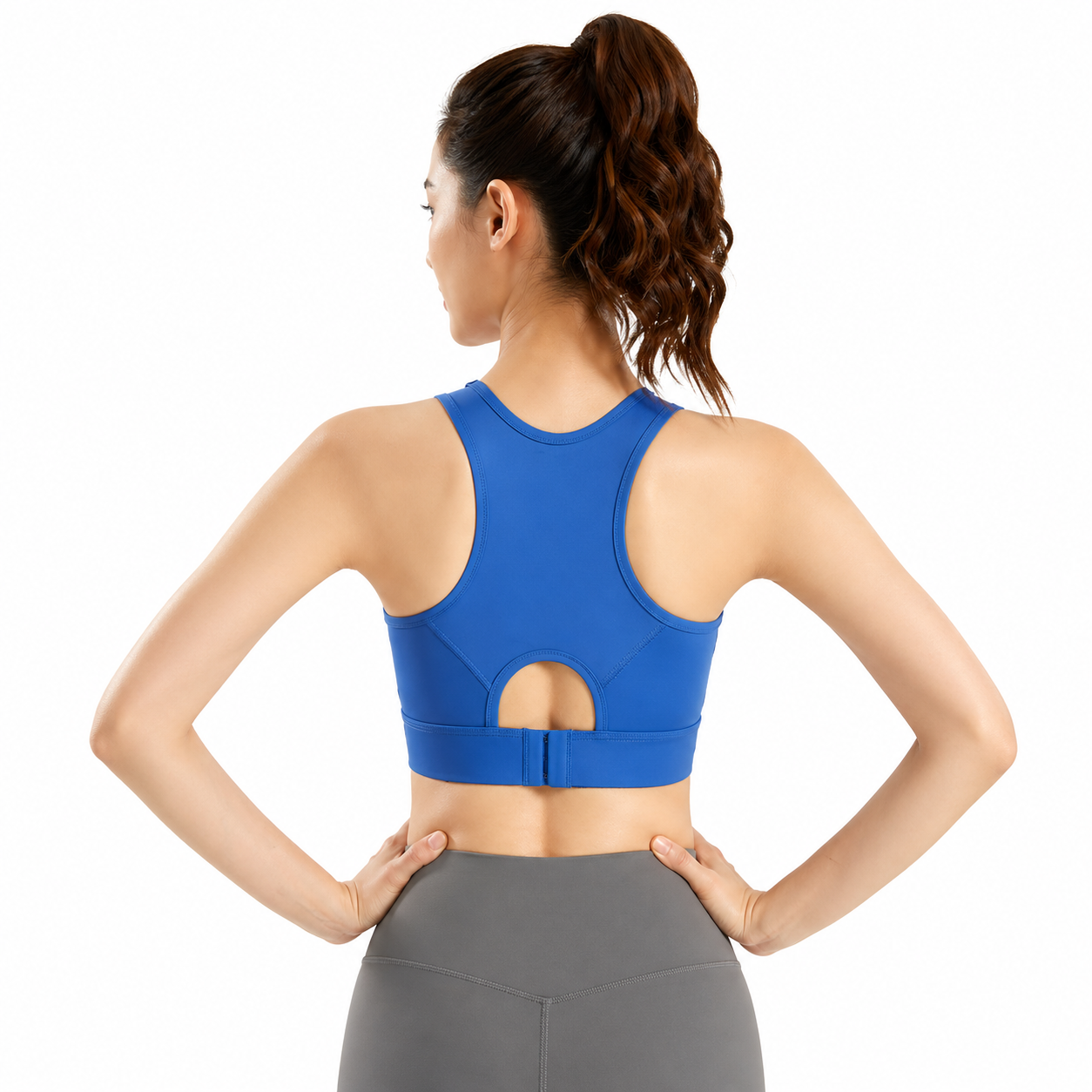Woman wearing a blue sports bra and gray leggings on a white background