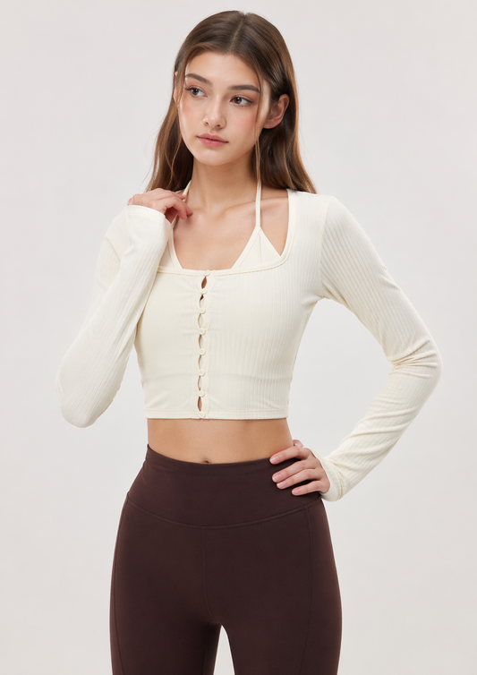 Woman wearing a cream long-sleeve crop top and dark leggings on a light gray background