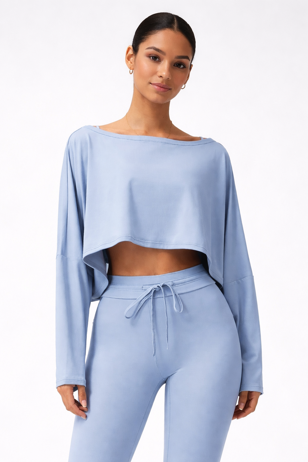 Woman wearing a light blue long-sleeve top and pants on a white background